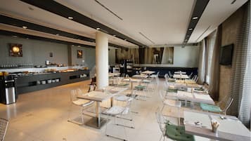 A modern dining area with a buffet, multiple tables, and chairs.