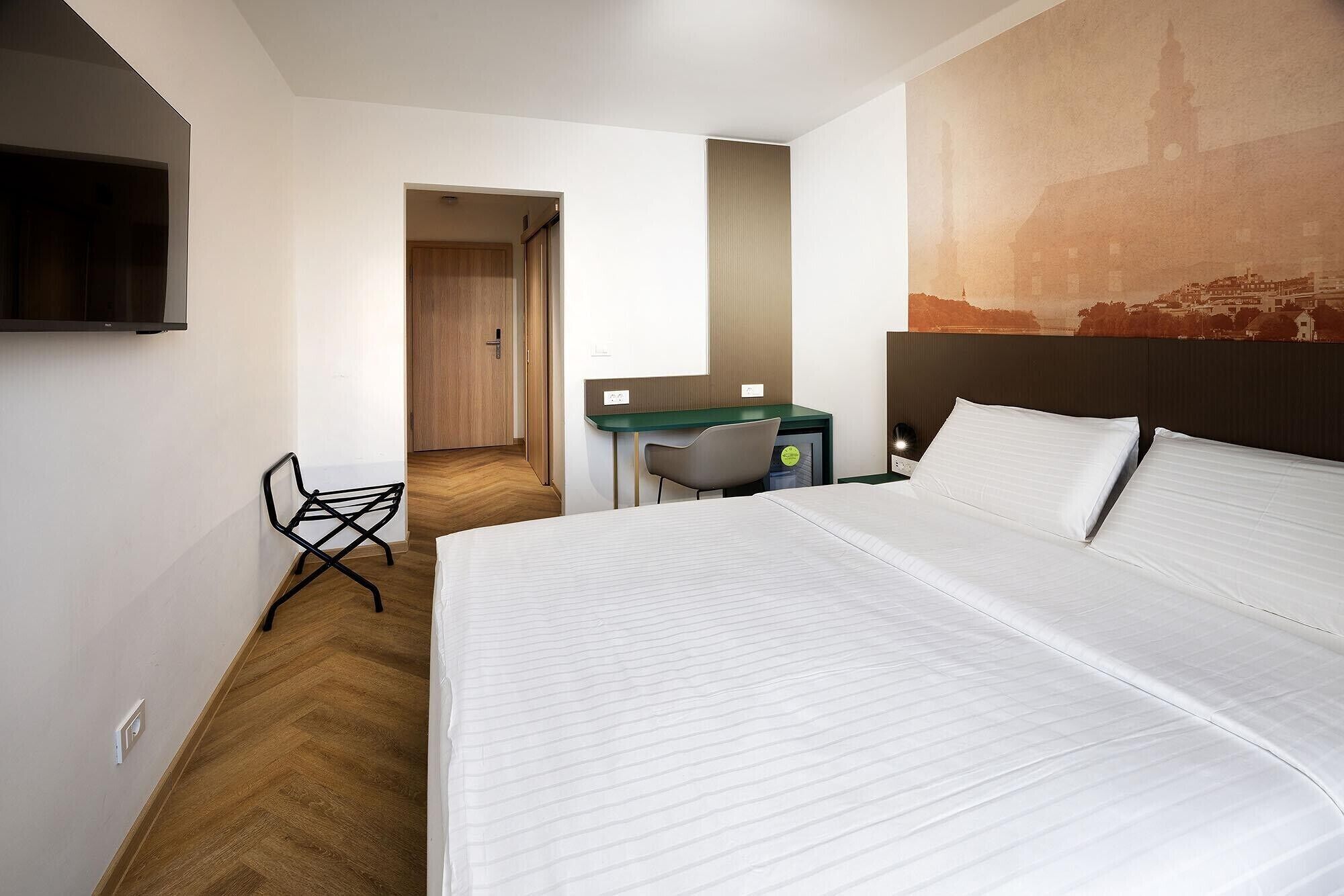 Una habitación de hotel con cama, escritorio, silla y televisor.