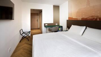 A hotel room with a bed, a desk, a chair, and a television.