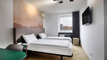 A hotel room with two beds, a TV, a window with curtains, and a cityscape view.