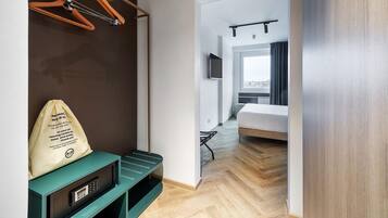 Een hotelkamer met een bed, een televisie, een houten vloer en uitzicht op de stad.