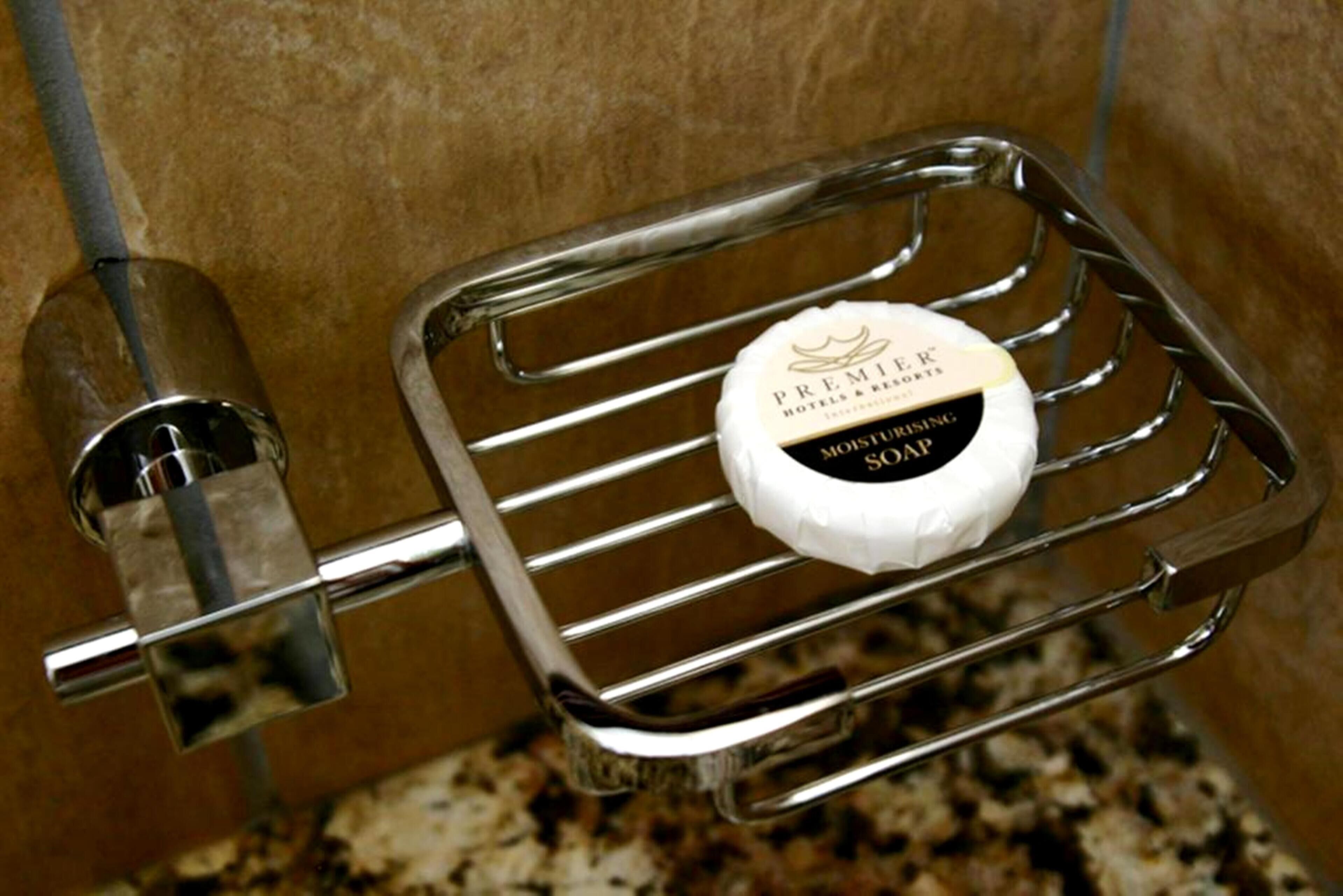 A soap bar in a chrome soap dish mounted on a wall.