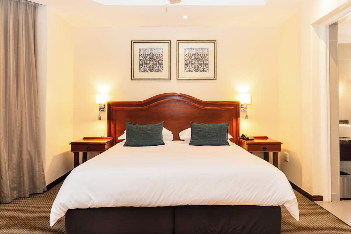 A hotel room with a large bed, two bedside tables with lamps, and two framed pictures on the wall.
