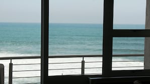 A view through a window of the ocean, with a railing in the foreground. - Premier Hotel Regent (East London)