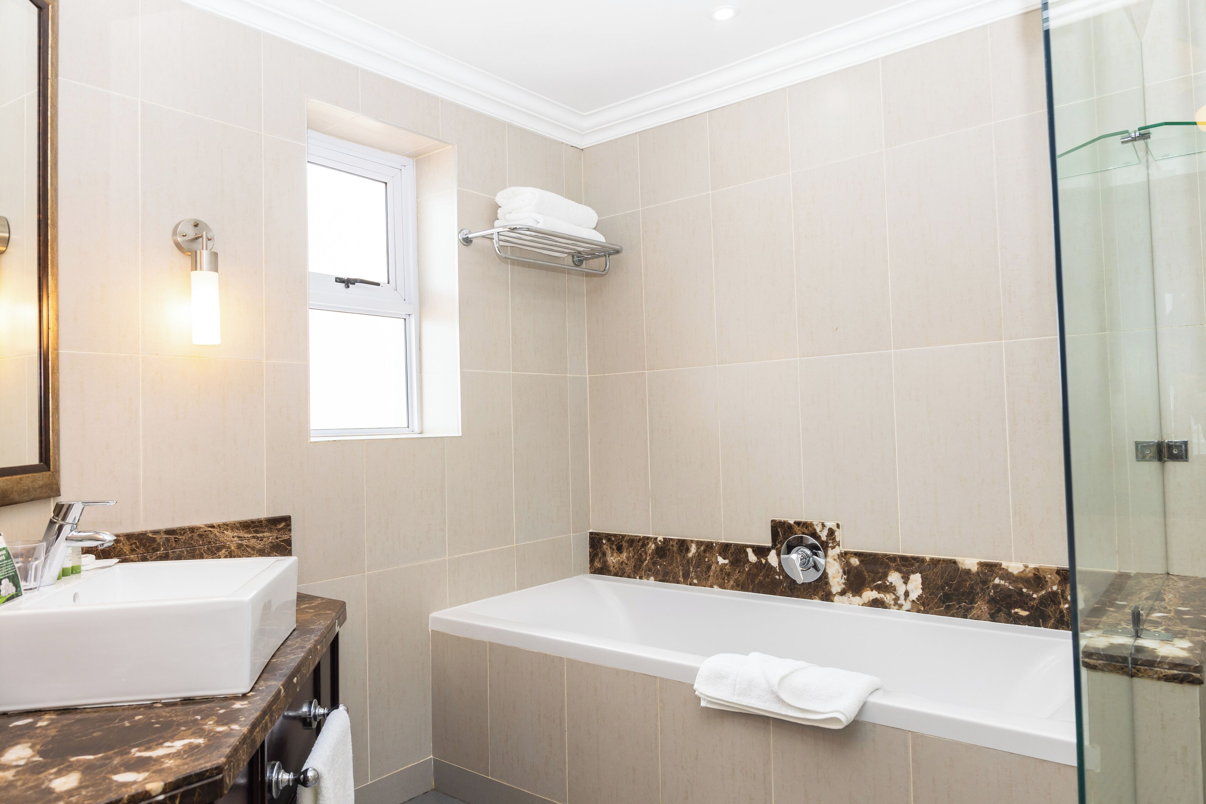 A modern bathroom with a large bathtub, a separate sink, and a glass shower enclosure.