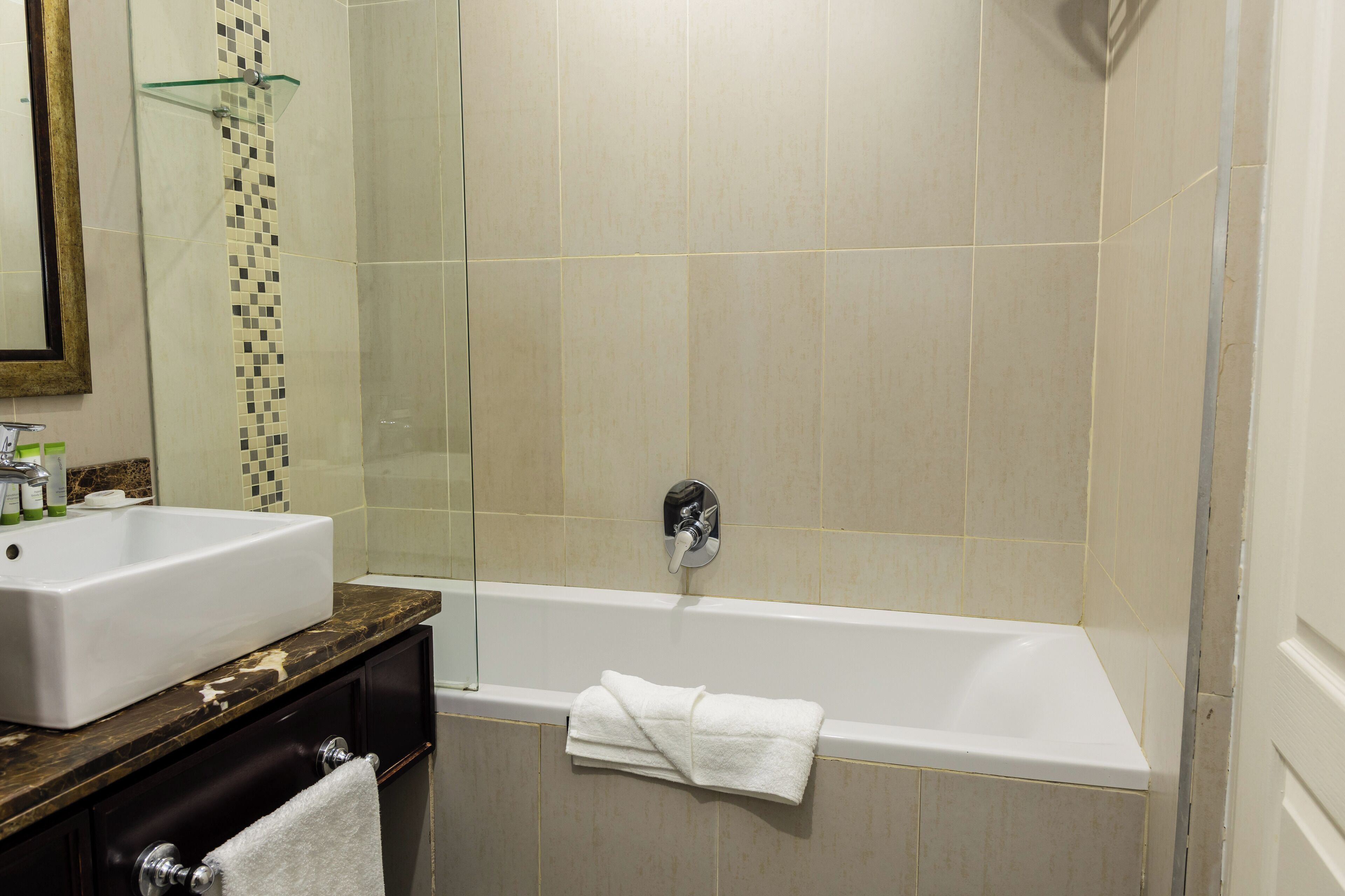 A bathroom with a bathtub, a sink, and a glass shower enclosure.
