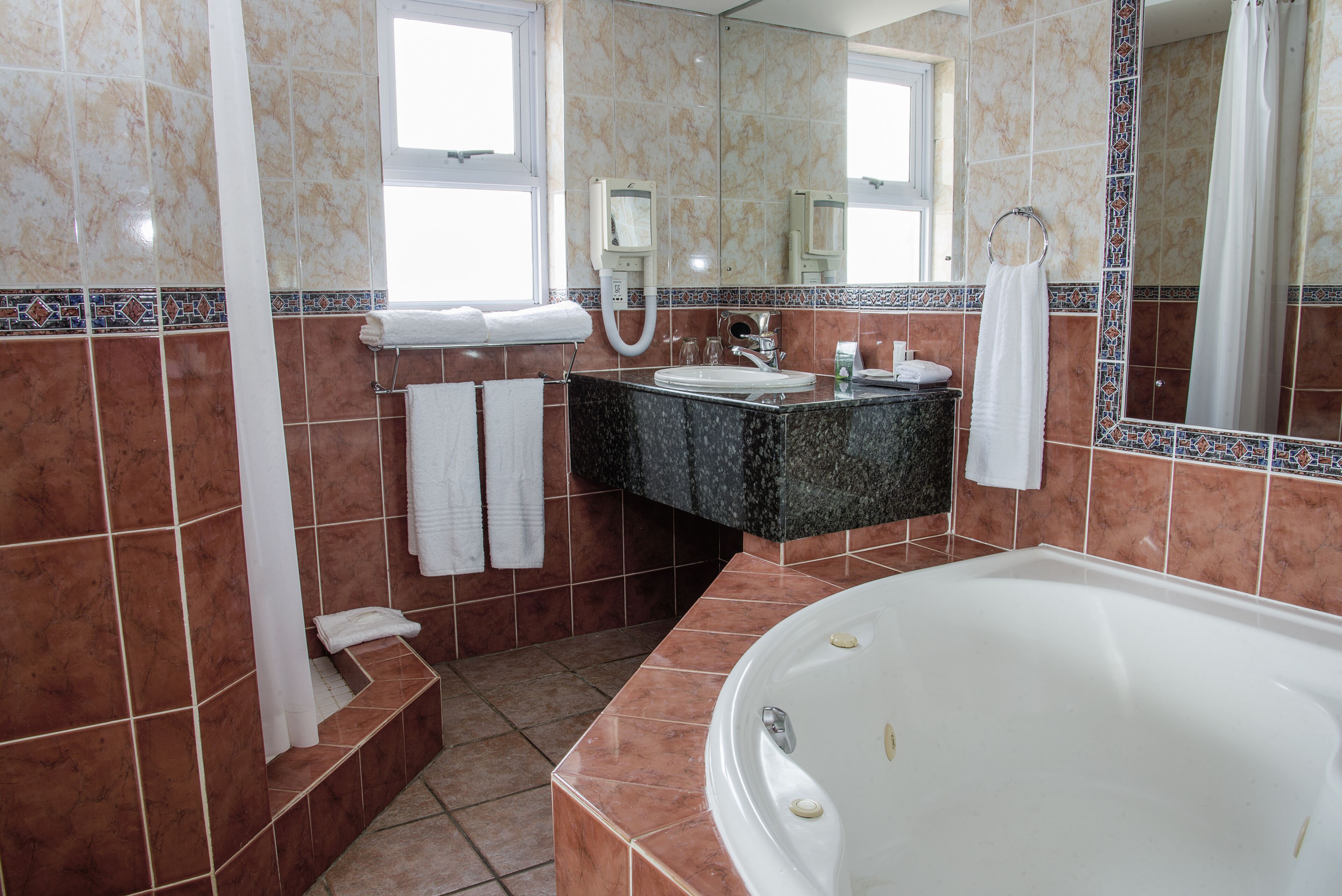 A bathroom with a bathtub, a sink, a mirror, and a shower.