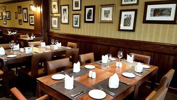 Ein Restaurant mit Holztischen und -stühlen, ordentlich gedeckt mit weißen Servietten, Tellern und Besteck.