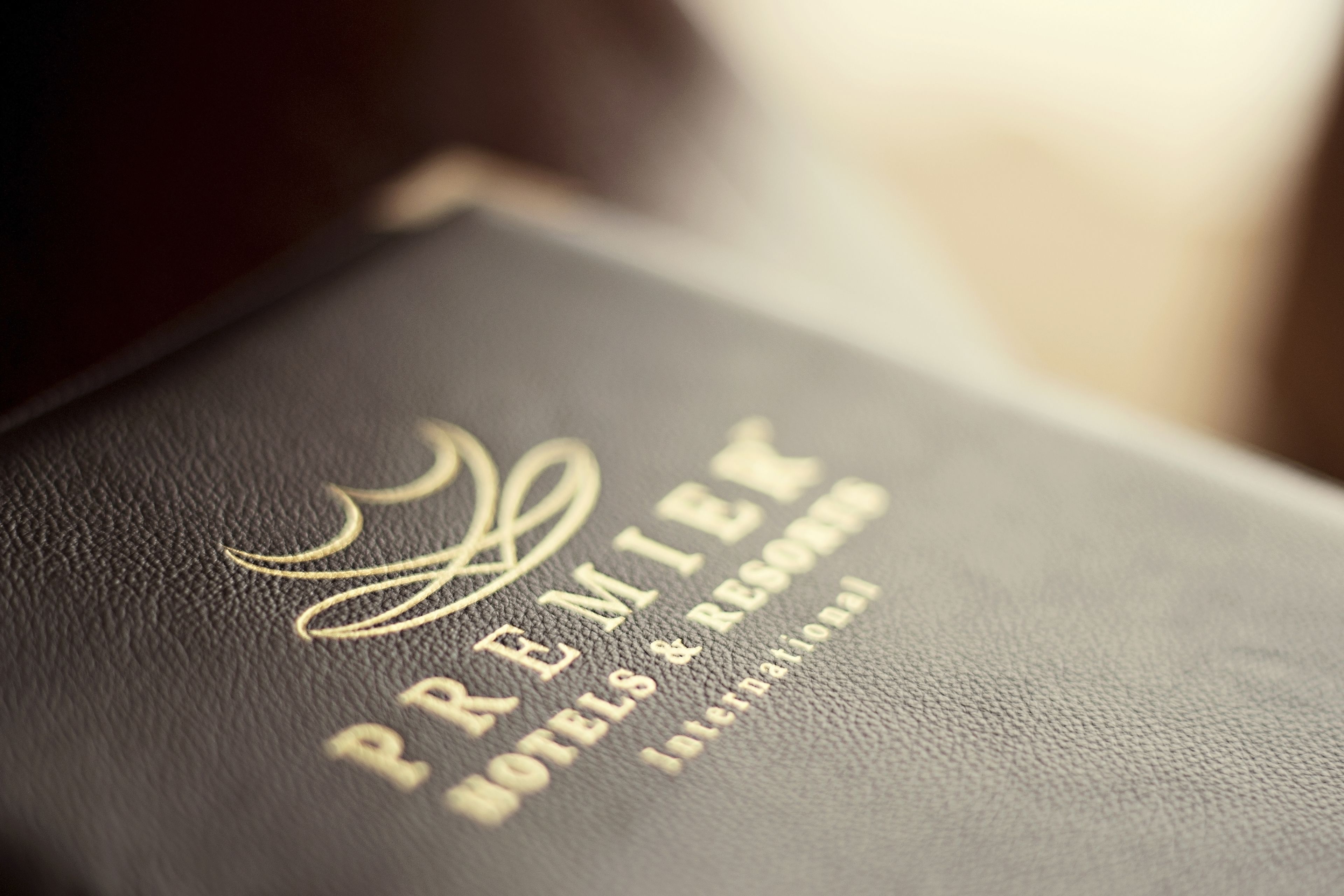 Un libro encuadernado en cuero negro con texto dorado grabado que dice "PREMIER HOTELS & RESORTS INTERNATIONAL".