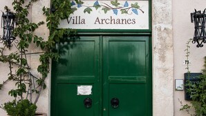Une porte à deux battants, peinte en vert, avec une enseigne au-dessus indiquant « Villa Archances ».