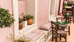 Un espace extérieur accueillant, aménagé avec des pots en terre cuite, des chaises en bois et un banc en pierre.