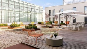 Une terrasse extérieure moderne, aménagée avec des sièges, des jardinières et un grand parasol.