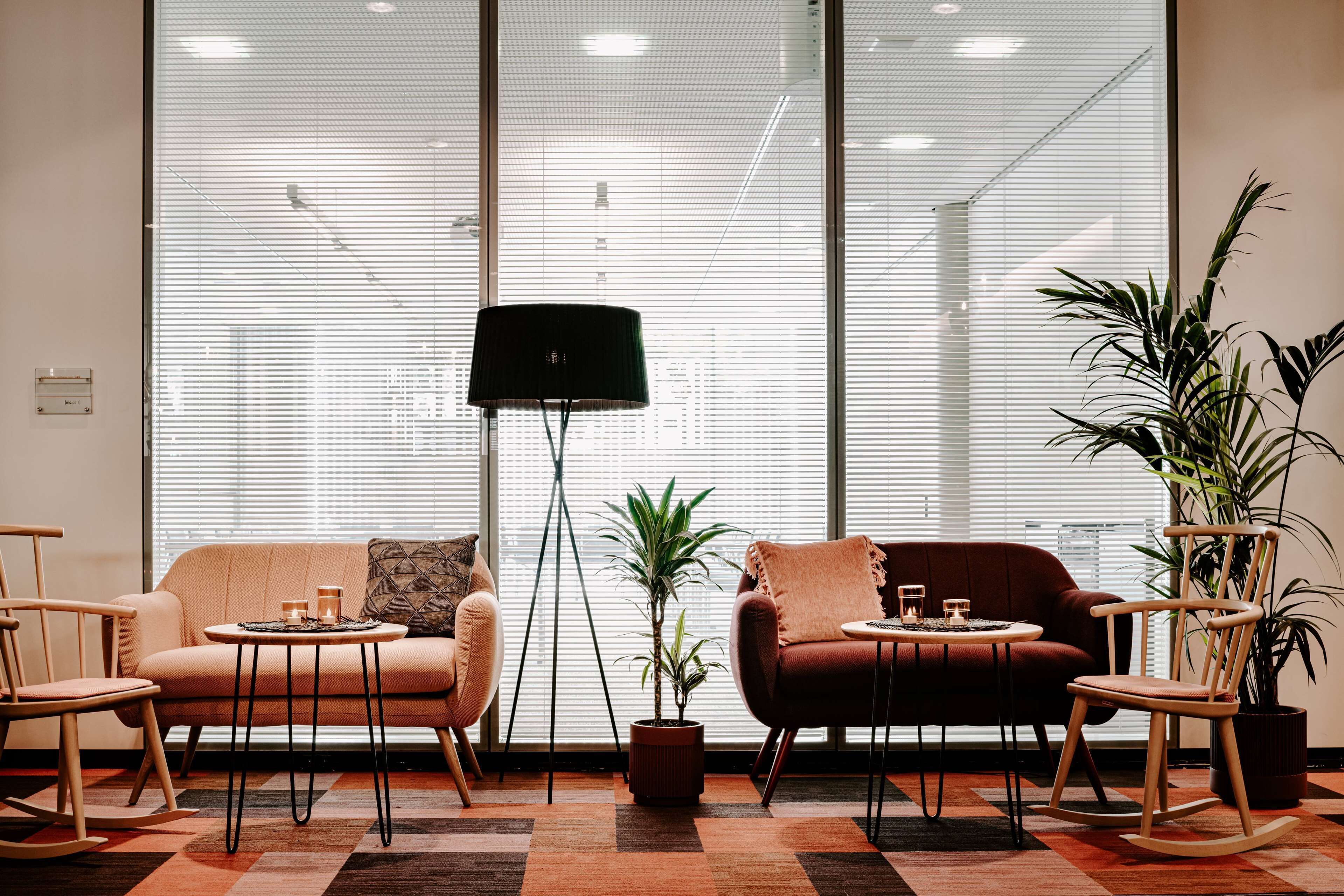En moderne stue med sofa, stole, et lille bord og en gulvlampe.