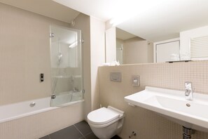 A modern bathroom with a glass-enclosed shower, a white toilet, and a sink with a mirror above. - Vienna House Easy by Wyndham Stuttgart (Stuttgart)