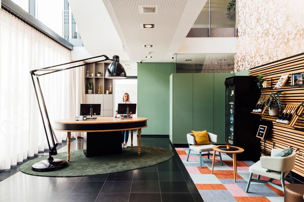 A modern office space with a round table, a standing desk, and a seating area with a small table and chairs. - Vienna House Easy by Wyndham Stuttgart (Stuttgart)