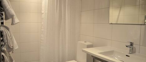 Un baño con inodoro blanco, lavamanos y cortina de ducha.