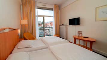 Une chambre d’hôtel avec deux lits, une chaise, une télévision et une petite table.