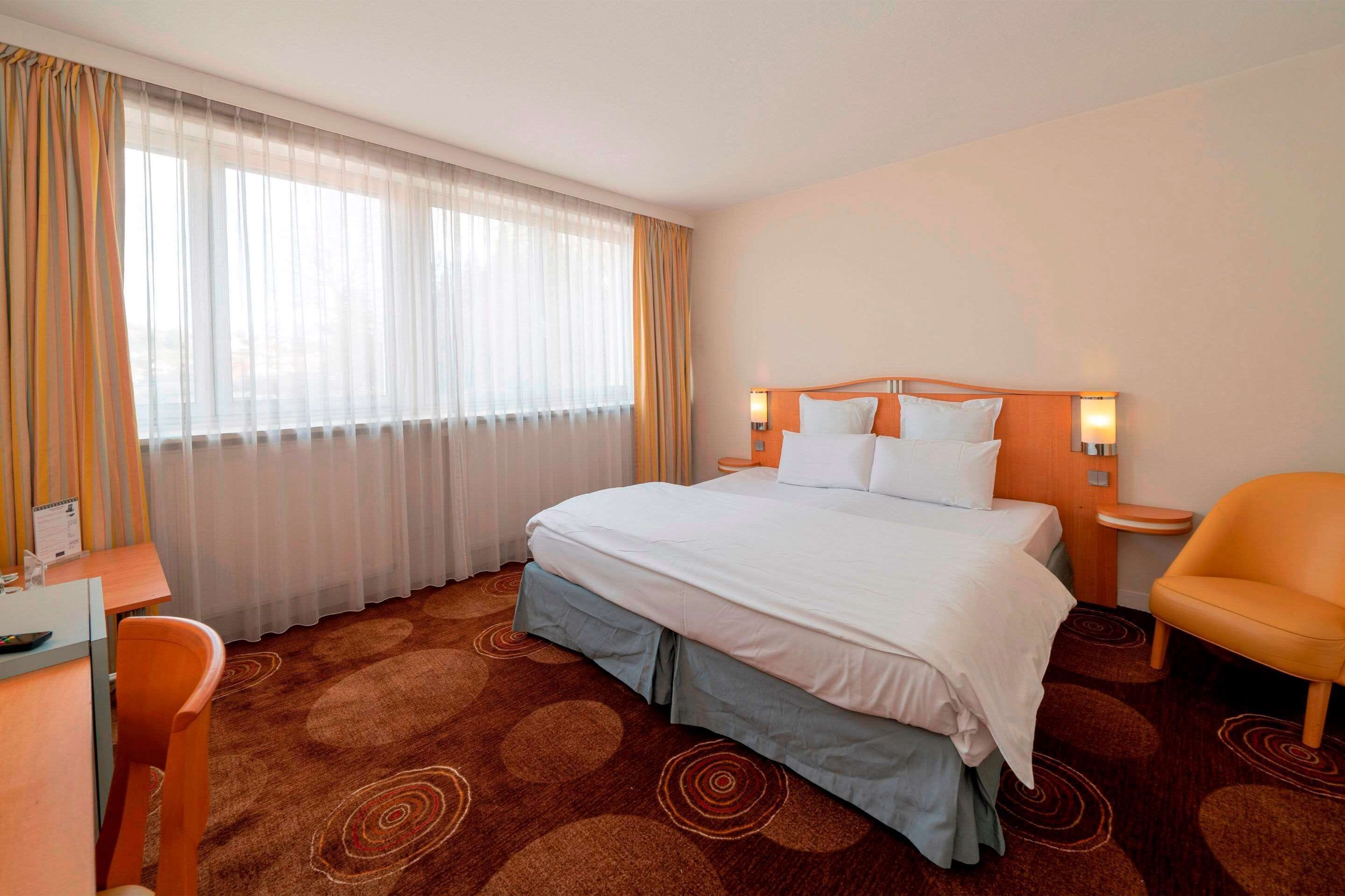 Ein Hotelzimmer mit einem großen Bett, einem Schreibtisch und einem Stuhl.