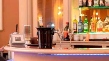 A bar area with a champagne bottle, two glasses, and a variety of liquor bottles on shelves.