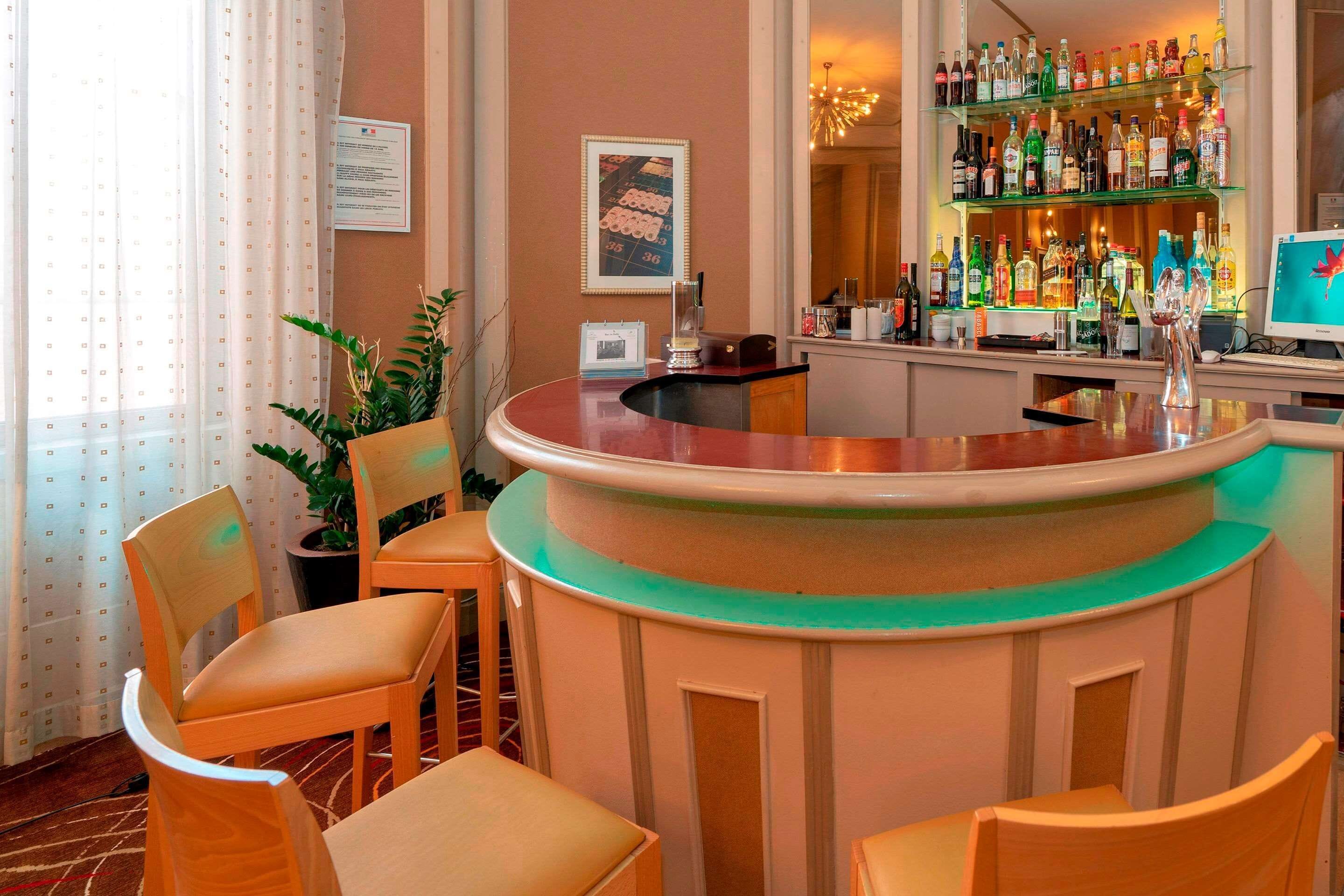 Eine Bar mit einer gebogenen Theke, mehreren Stühlen, einem Blumentopf und Regalen voller Flaschen.