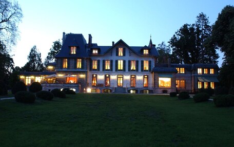 A large, multi-story building with a symmetrical facade, multiple windows, and a well-maintained lawn.