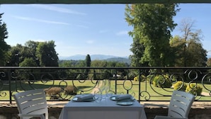 A table set for two with a view of a manicured lawn and distant mountains.