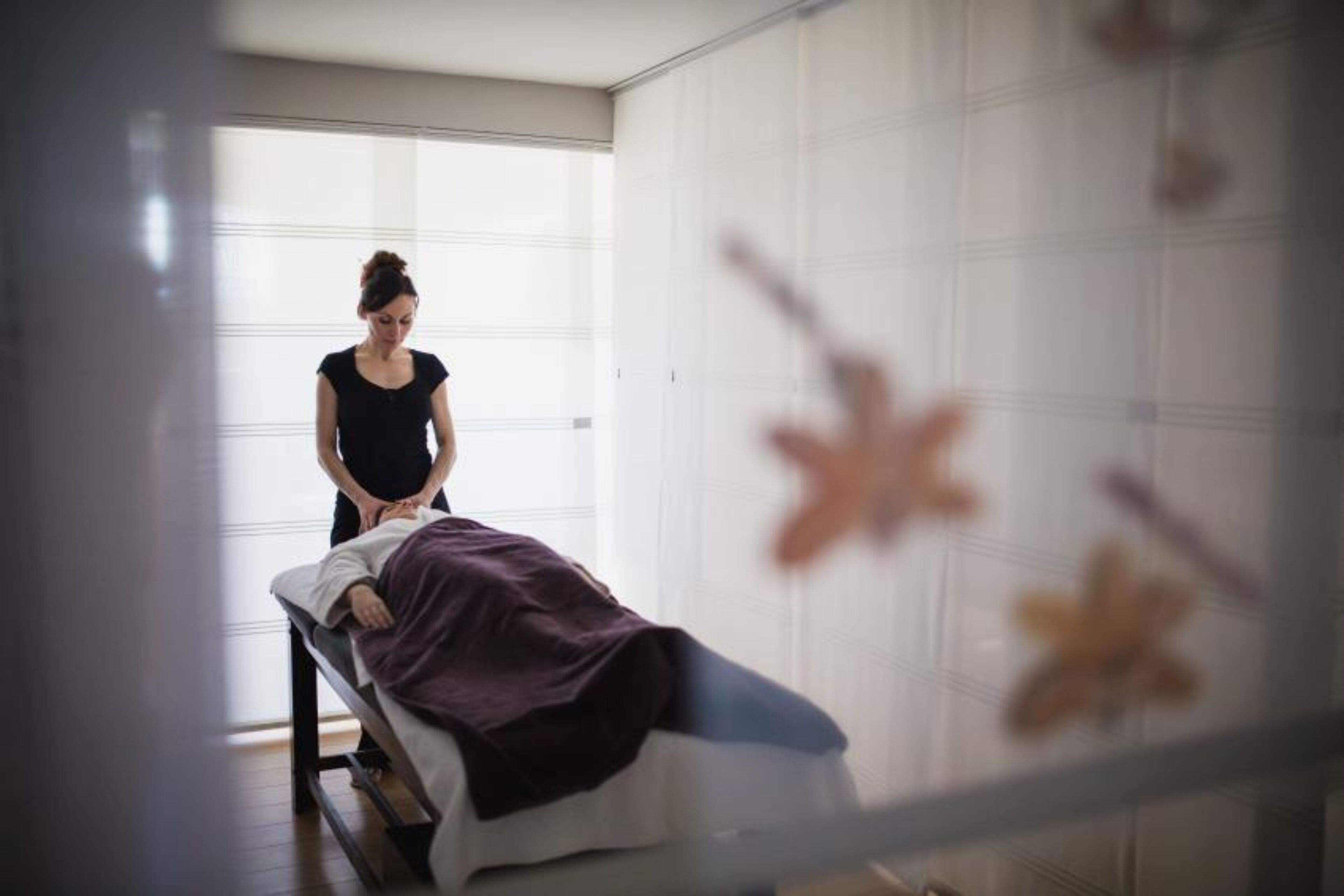Eine Person liegt in einem Zimmer mit weißen Wänden und einem Fenster auf einem Bett.
