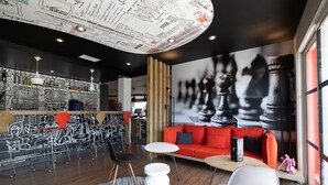 Un interior moderno con una zona de bar, asientos y un mural grande con un tablero de ajedrez.