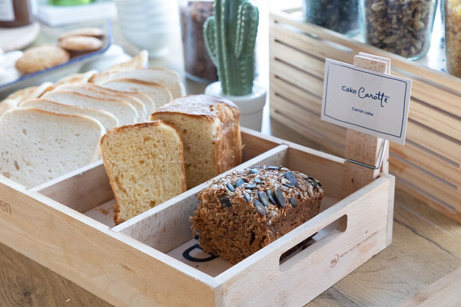 Una caja de madera para pan con diversos tipos de pan, incluyendo una hogaza con semillas por encima.
