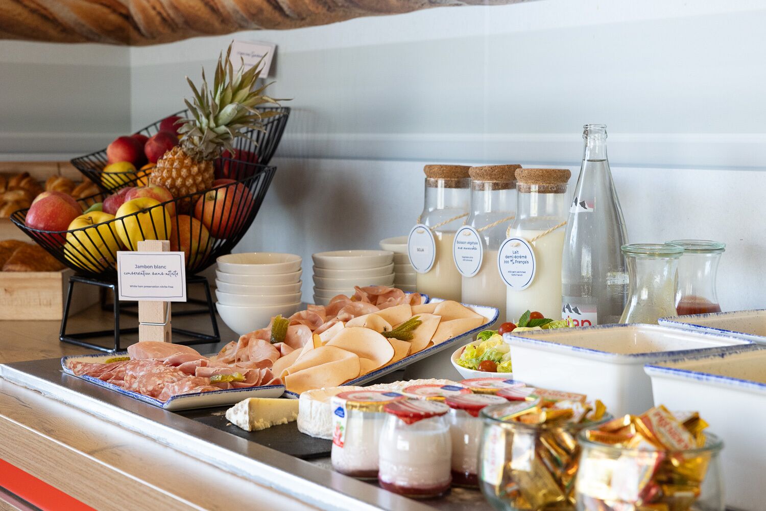 A buffet with various food items including meats, cheeses, fruits, and beverages.