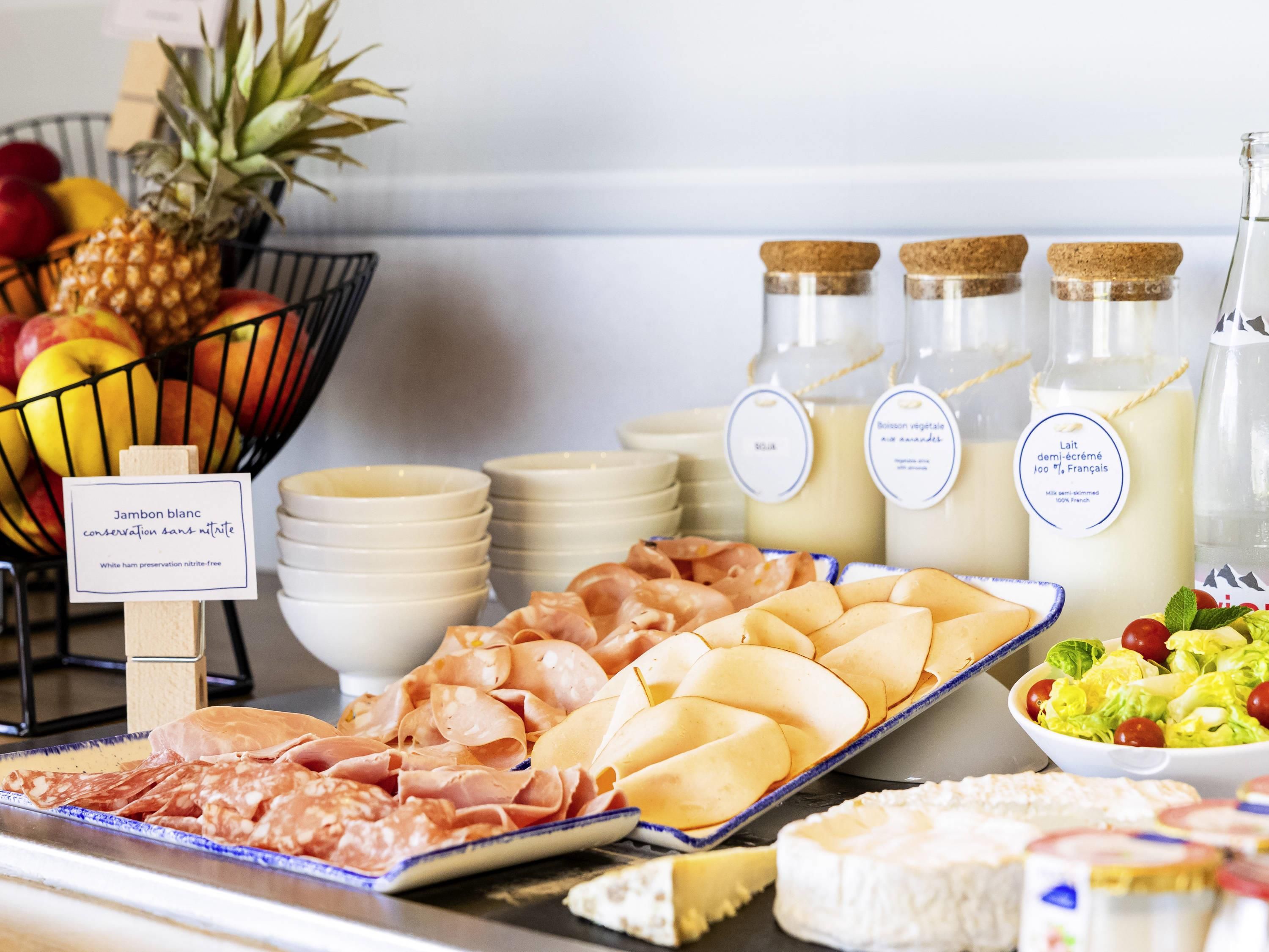Un buffet proposant une variété de plats, notamment des viandes, des fromages et des fruits.