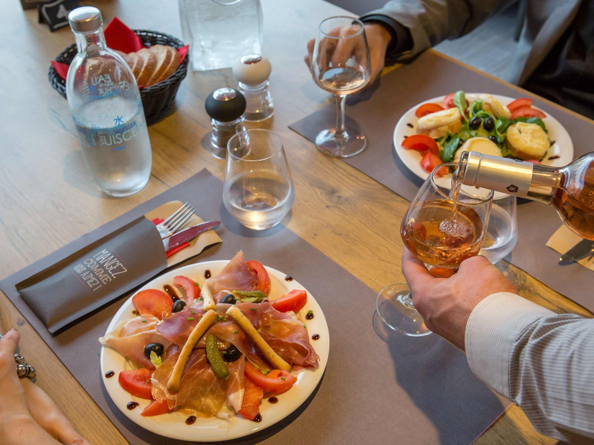 Una mesa de comedor con platos de comida, una botella de agua, saleros y pimenteros, y un menú.
