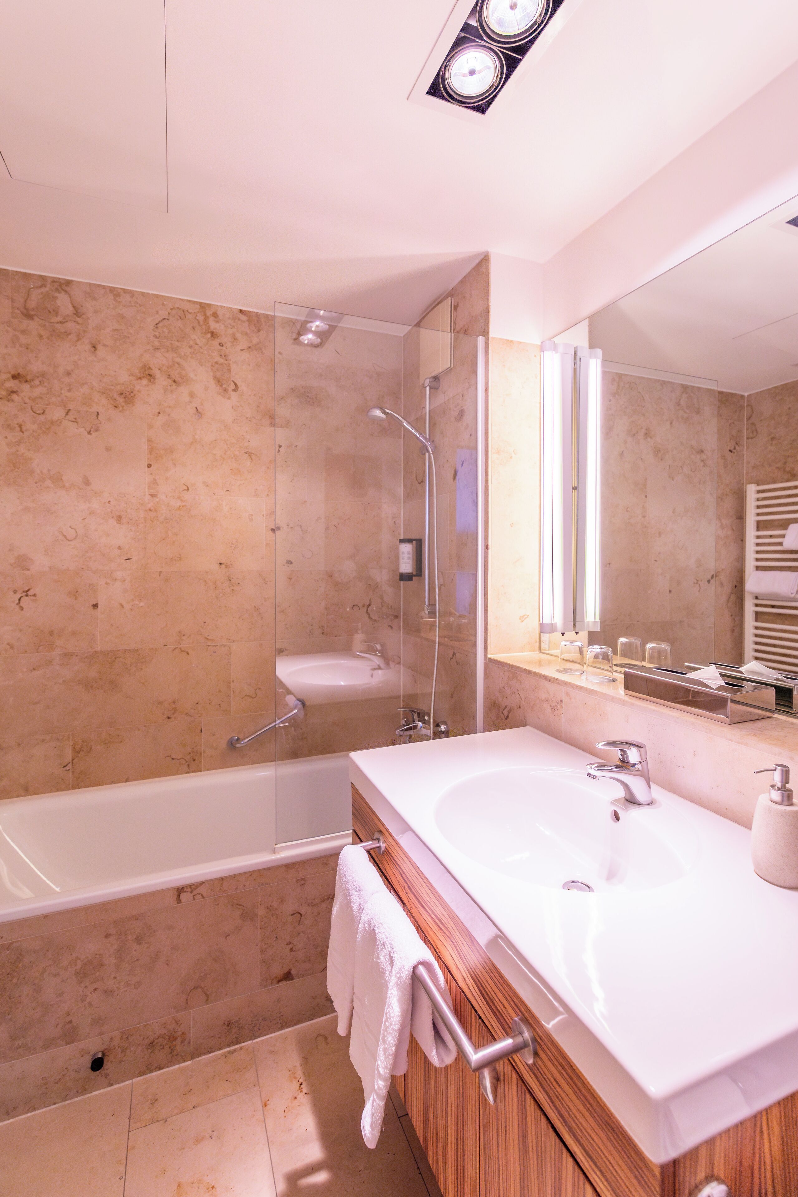 A modern bathroom with a bathtub, a large mirror, and a vanity with a sink.