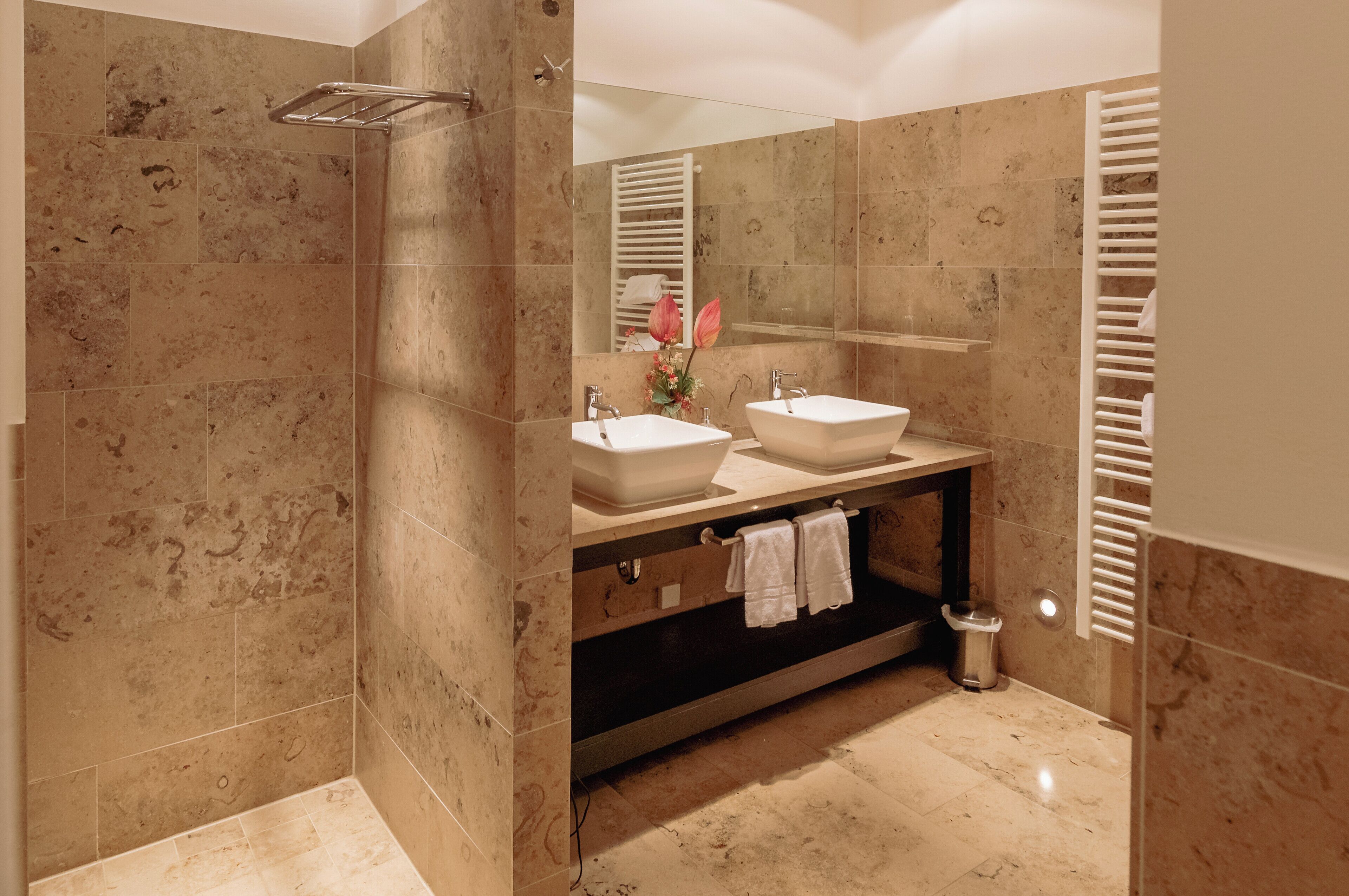A modern bathroom with two sinks, a shower, and a towel rack.