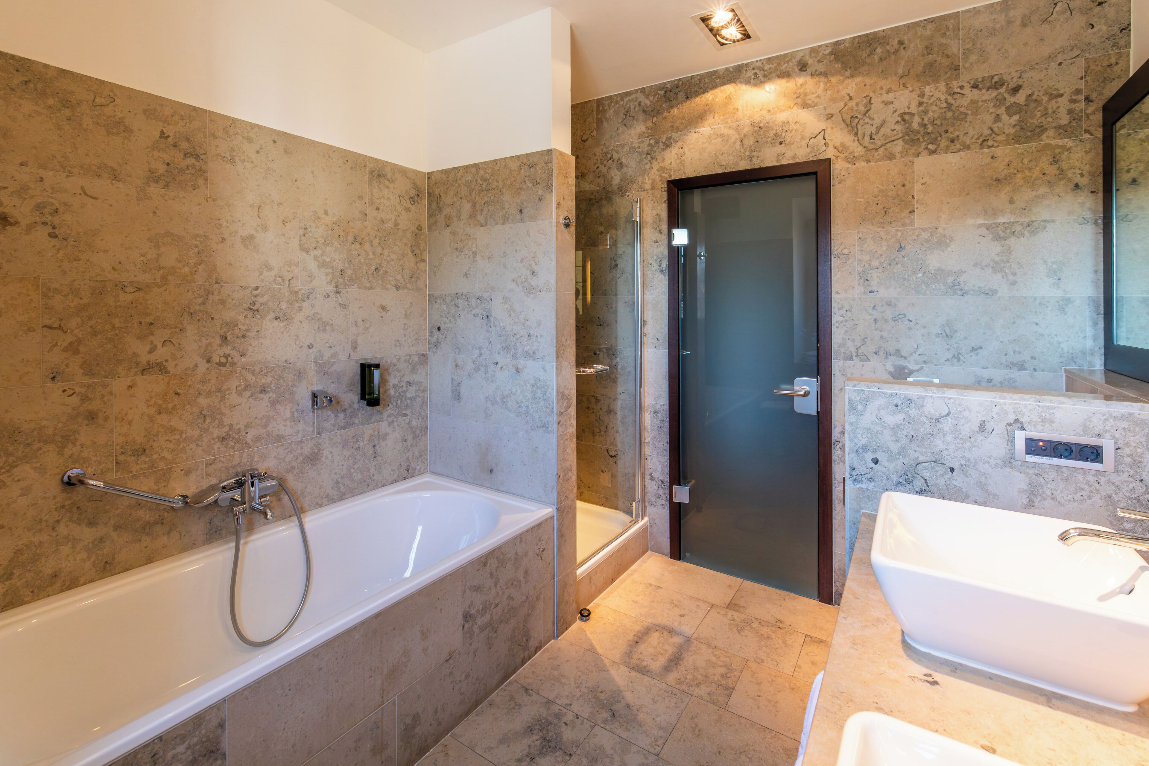A modern bathroom with a bathtub, a shower, and a sink.