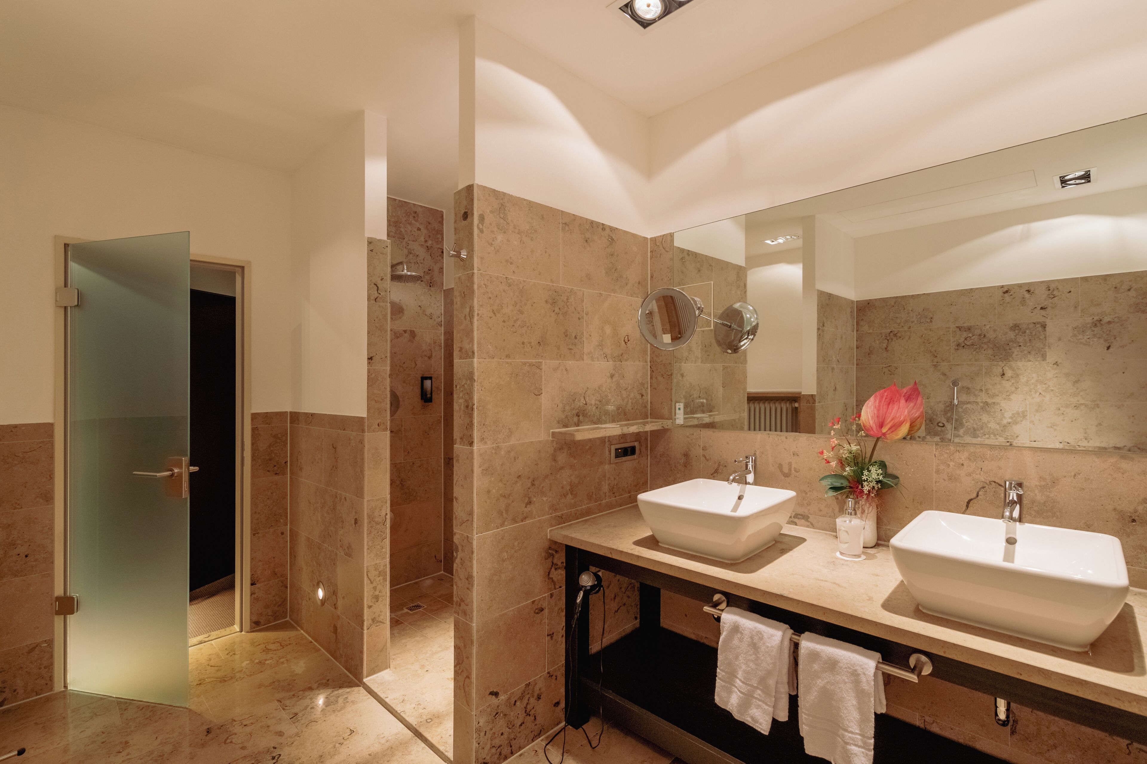Une salle de bain moderne avec deux lavabos, un grand miroir et un espace douche.