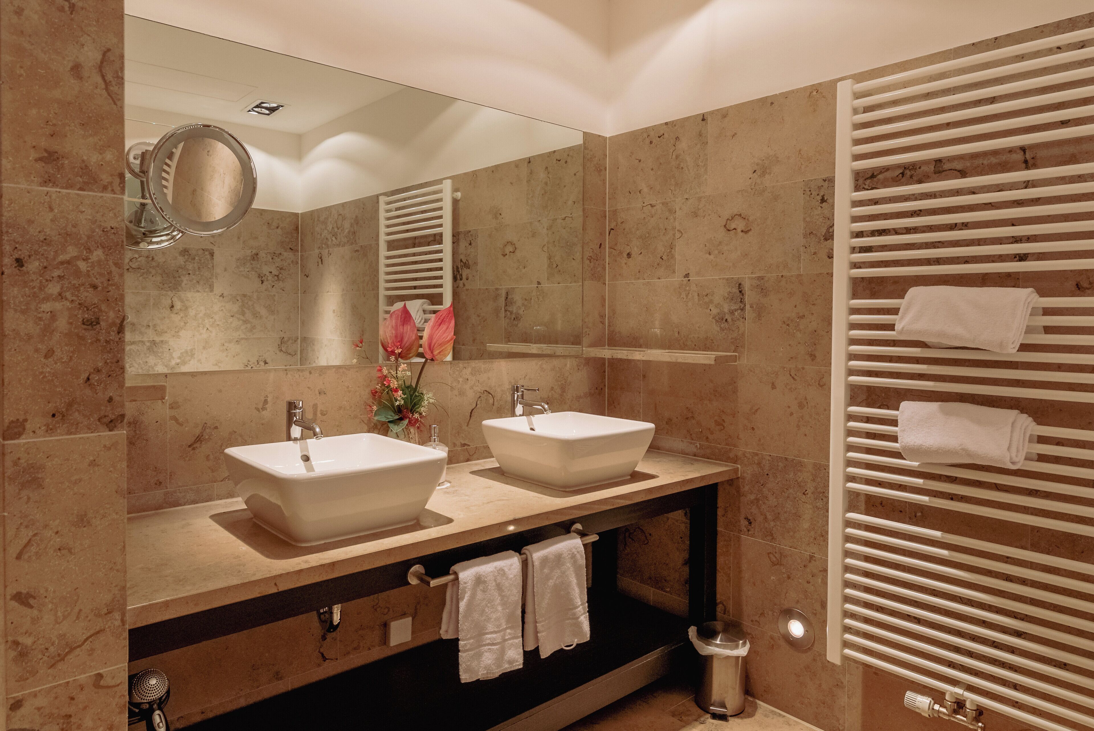 A bathroom with two sinks, a mirror, a towel rack, and a shower.