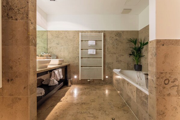 Un baño moderno con suelo de mármol, un lavamanos, un espejo, un perchero para toallas y una planta en maceta.