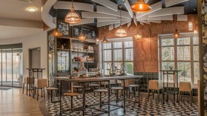 Ein Café mit einer zentralen Bar, mehreren hängenden Pendelleuchten und einem gemusterten Boden.