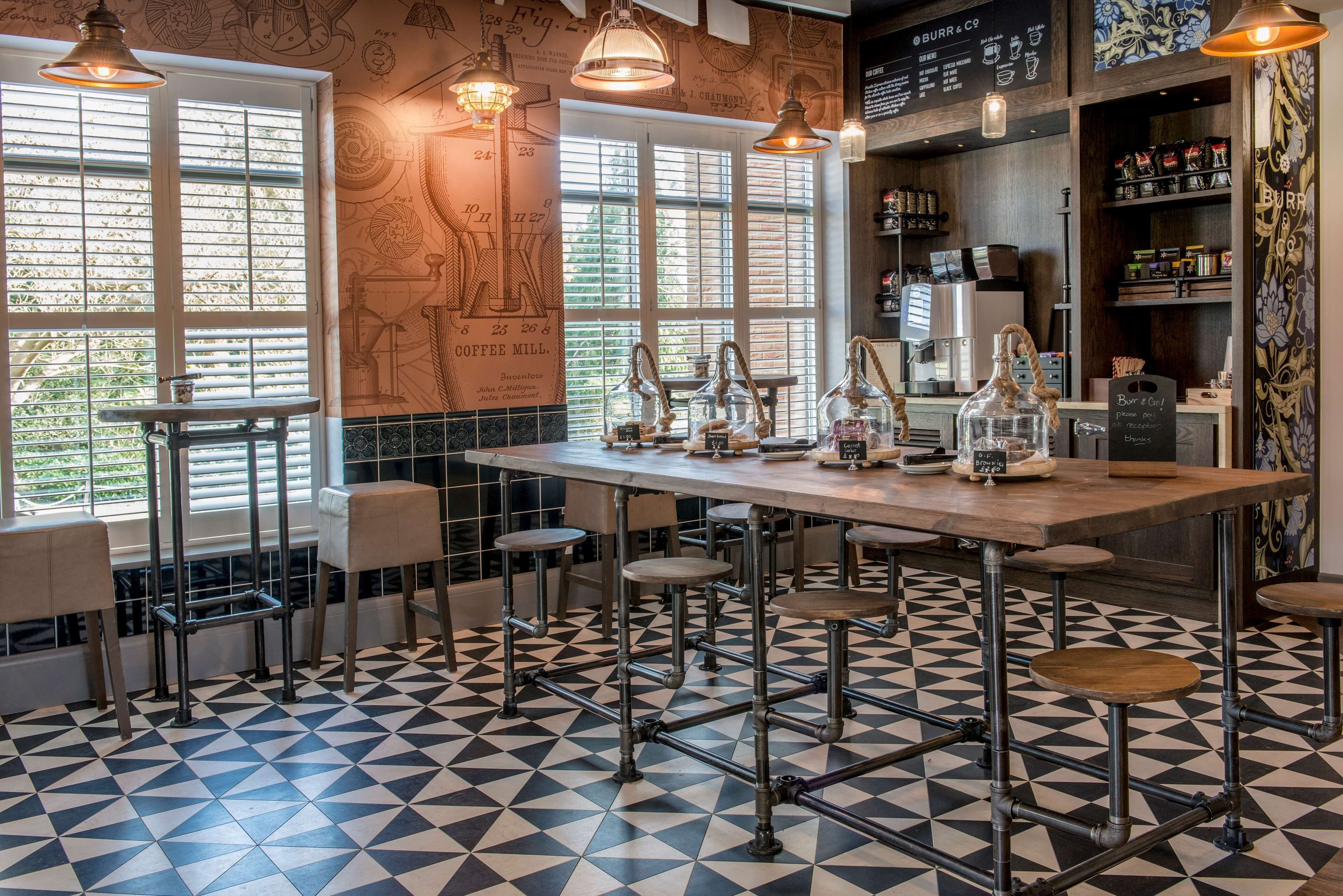 Una zona de bar con suelo a cuadros, taburetes y lámparas colgantes.