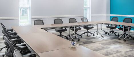 A conference room with a long table, multiple chairs, and a blue accent wall.