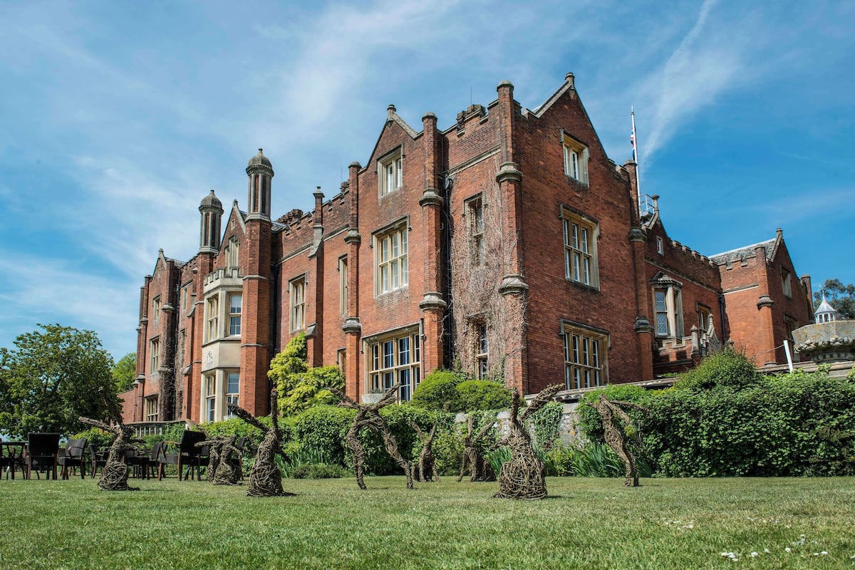 A large, historic brick building with multiple chimneys and a symmetrical facade.