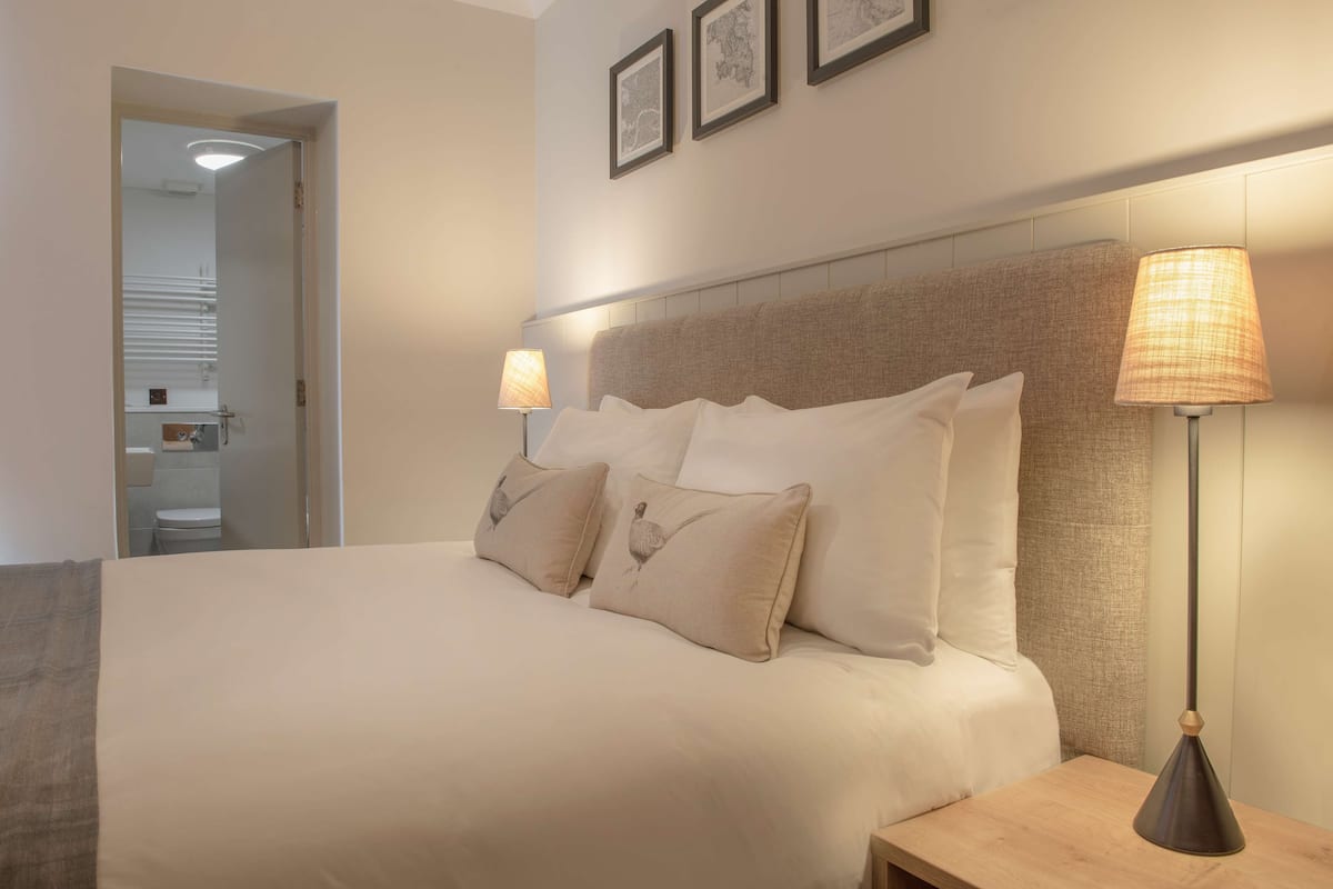 A neatly made bed with two pillows, a bedside lamp, and a framed picture on the wall.
