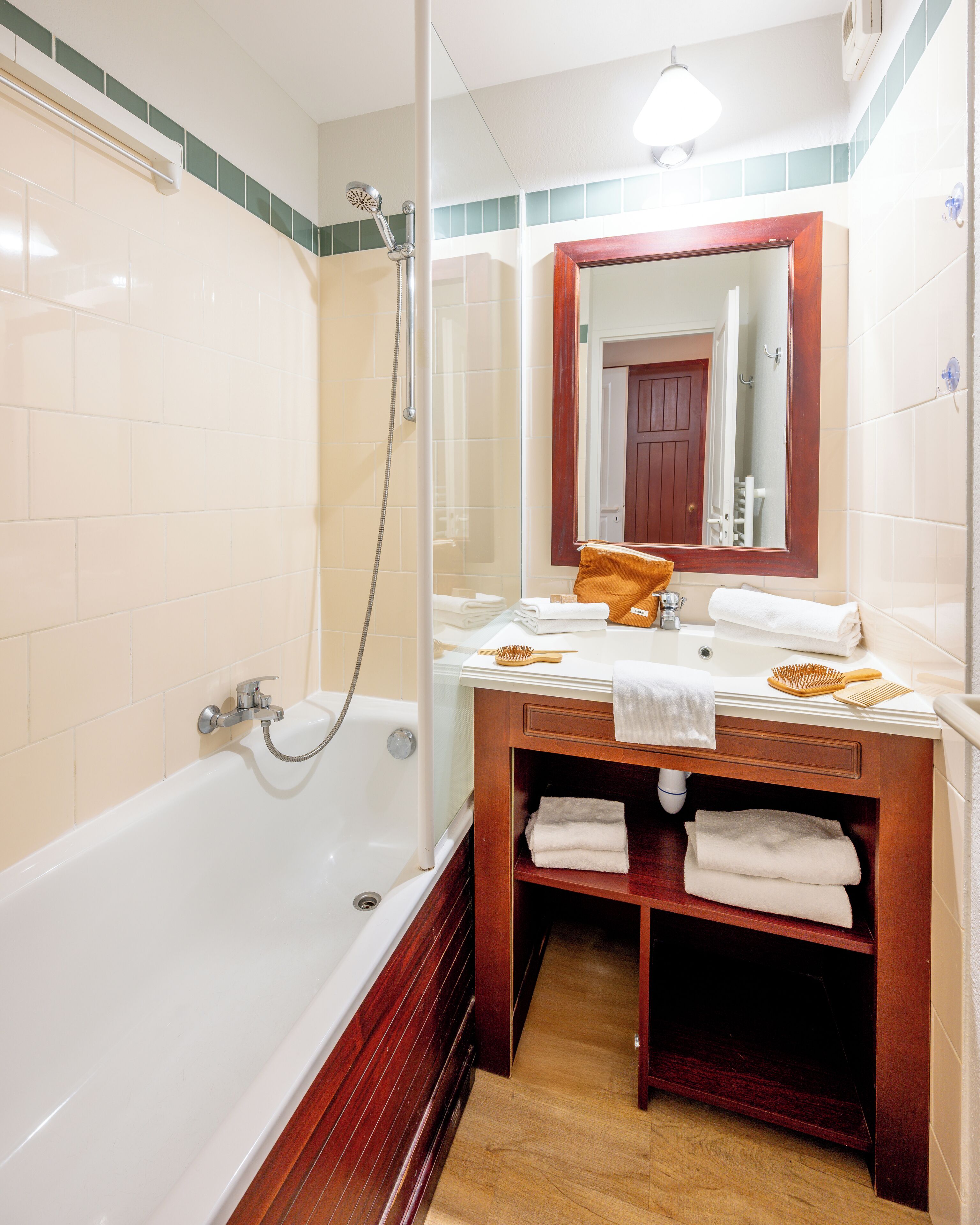 A bathroom with a bathtub, a shower, a vanity with a mirror, and a towel rack.