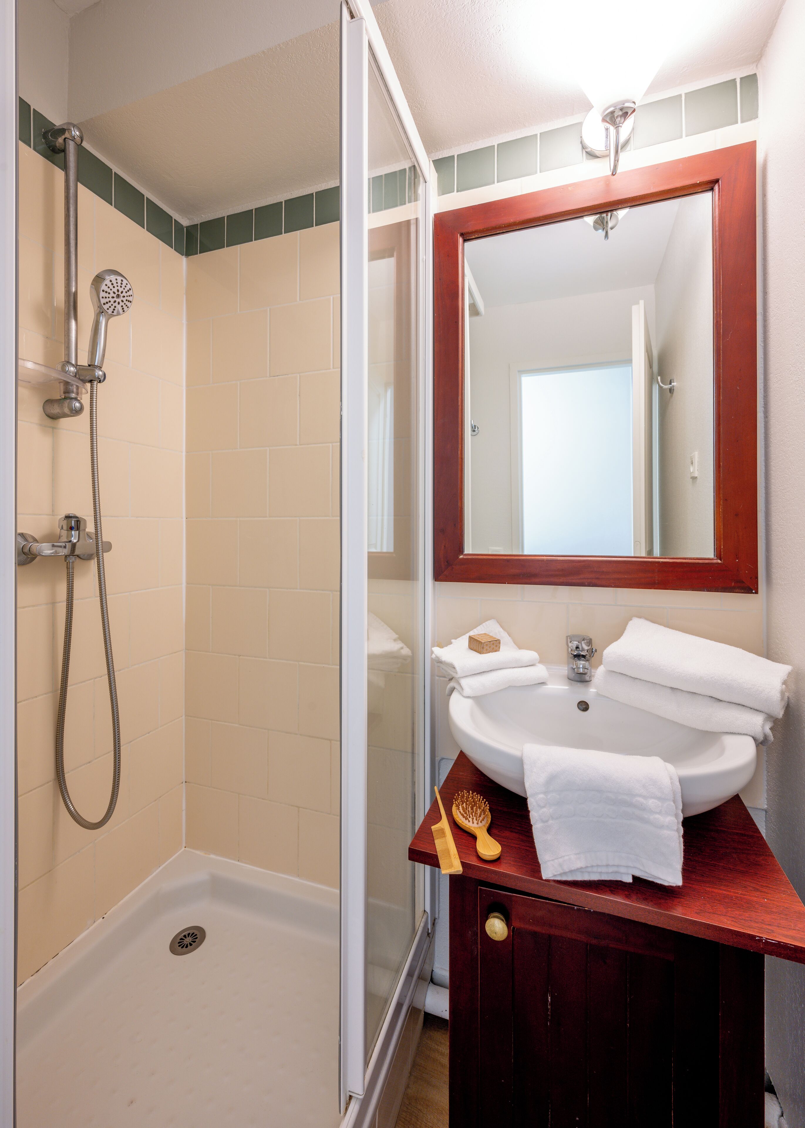 Een badkamer met een douche, wastafel en spiegel.