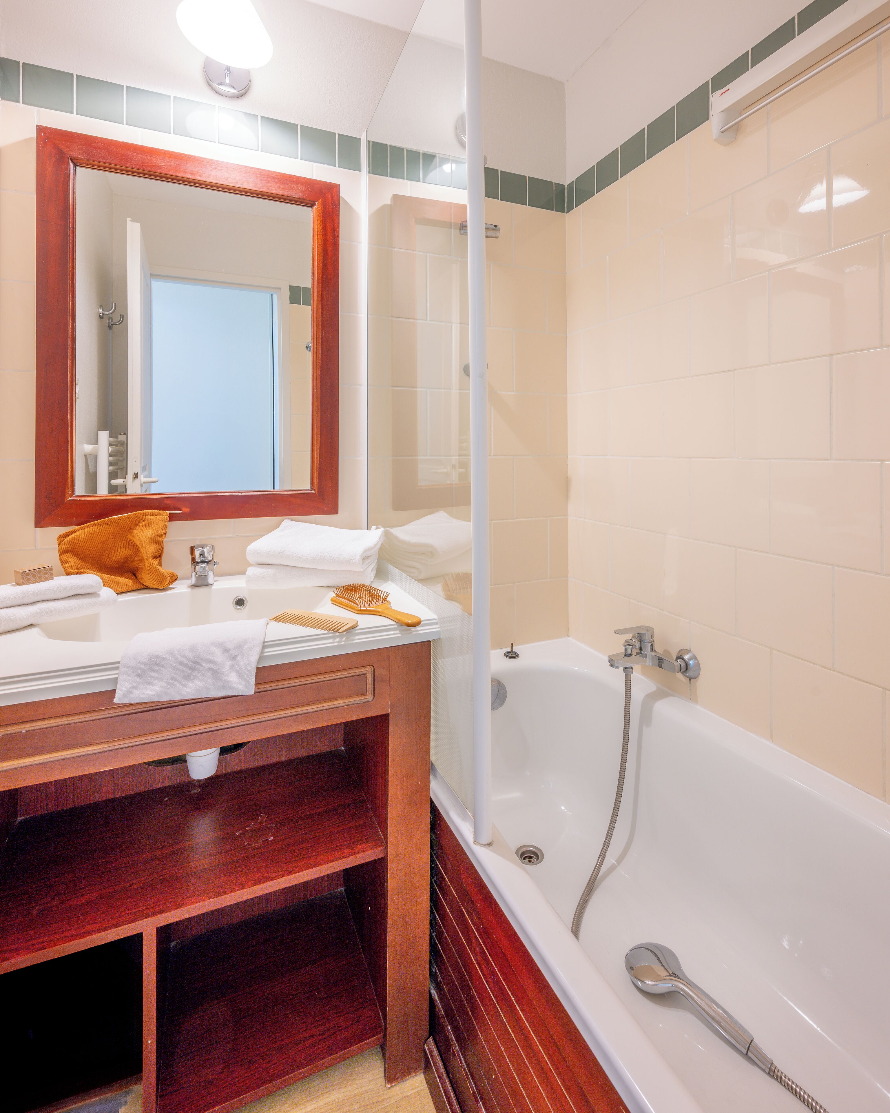 Ein Badezimmer mit einem Holzbadezimmermöbel, einem großen Spiegel, einer Badewanne und einer Duschkabine.