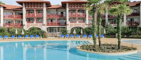 Een seizoensgebonden buitenzwembad en ligstoelen