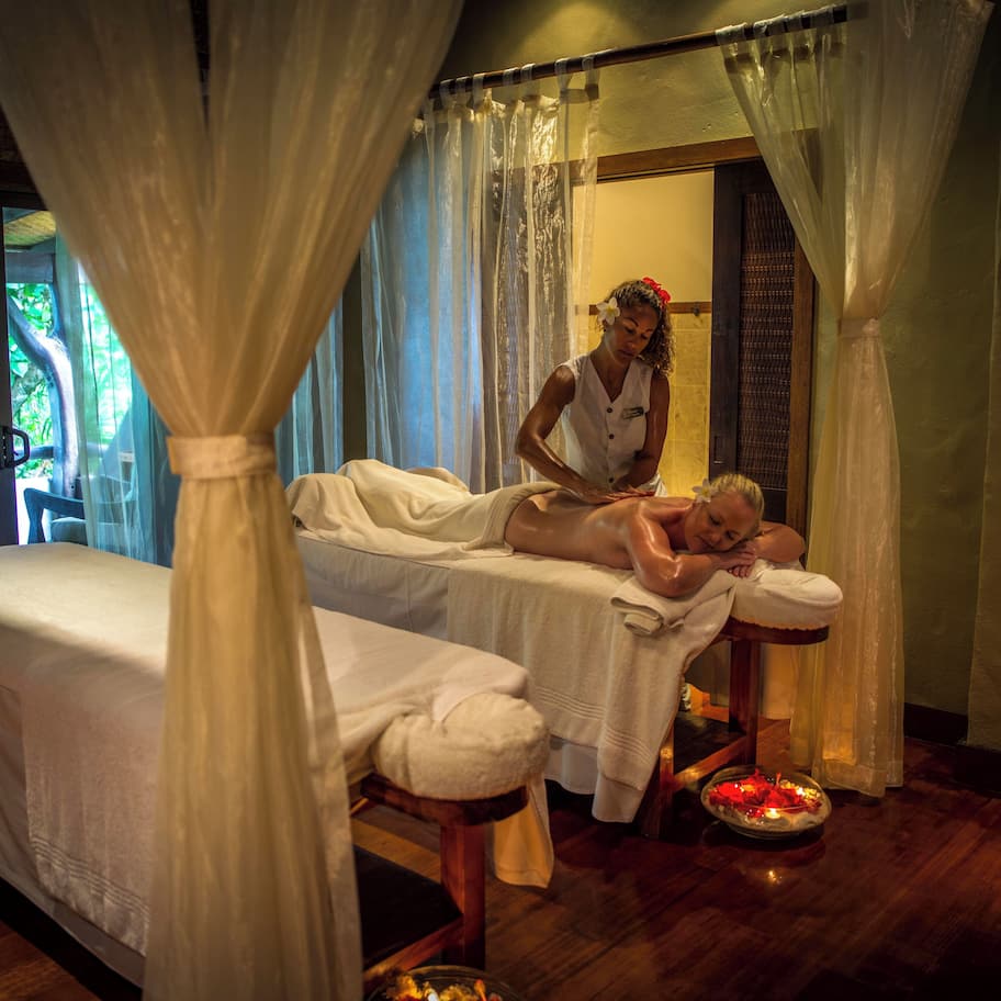 A room with a bed, a massage table, and a window with curtains.