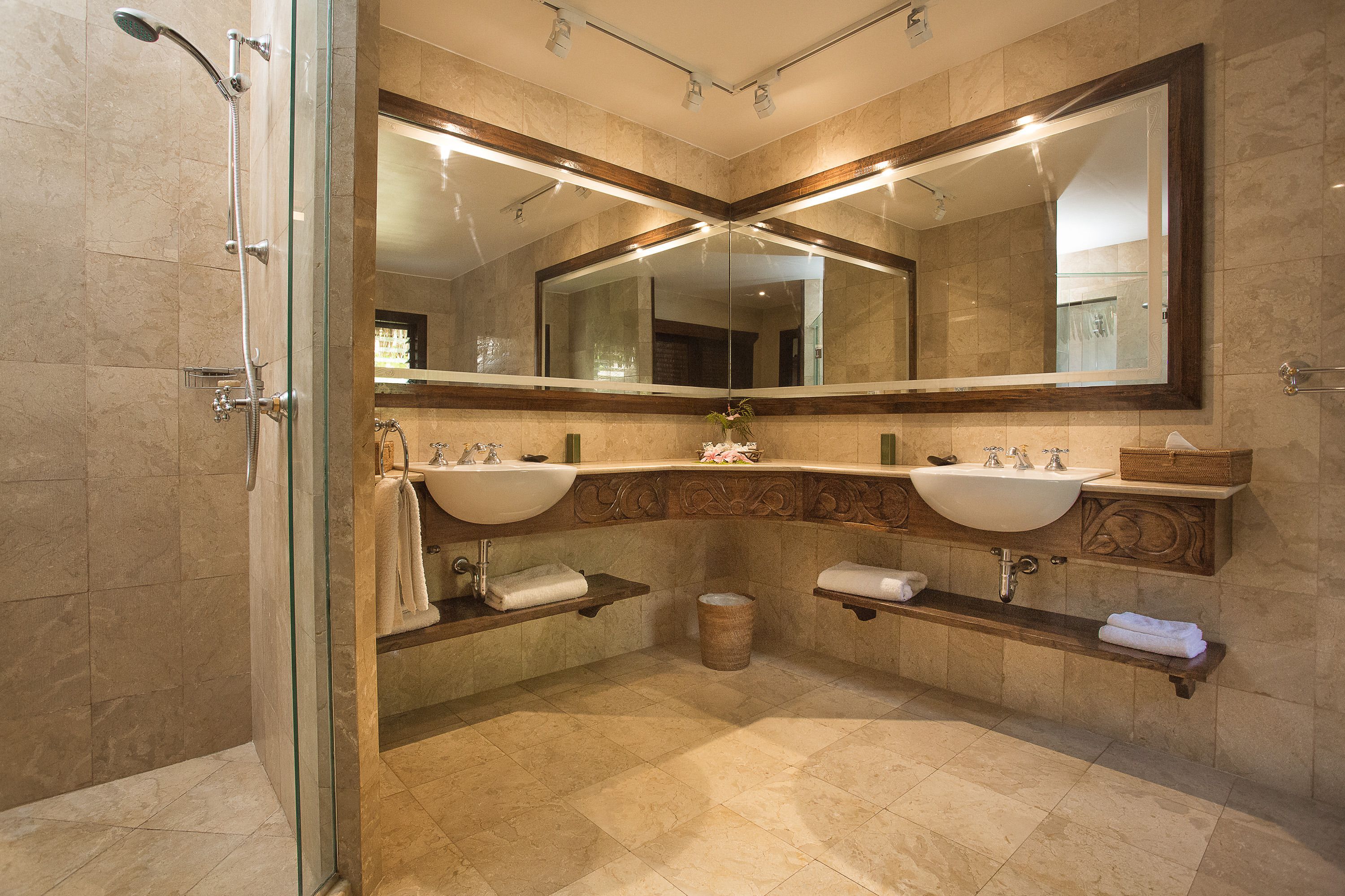 Un baño moderno con dos lavamanos, un espejo grande y una ducha con mampara de vidrio.