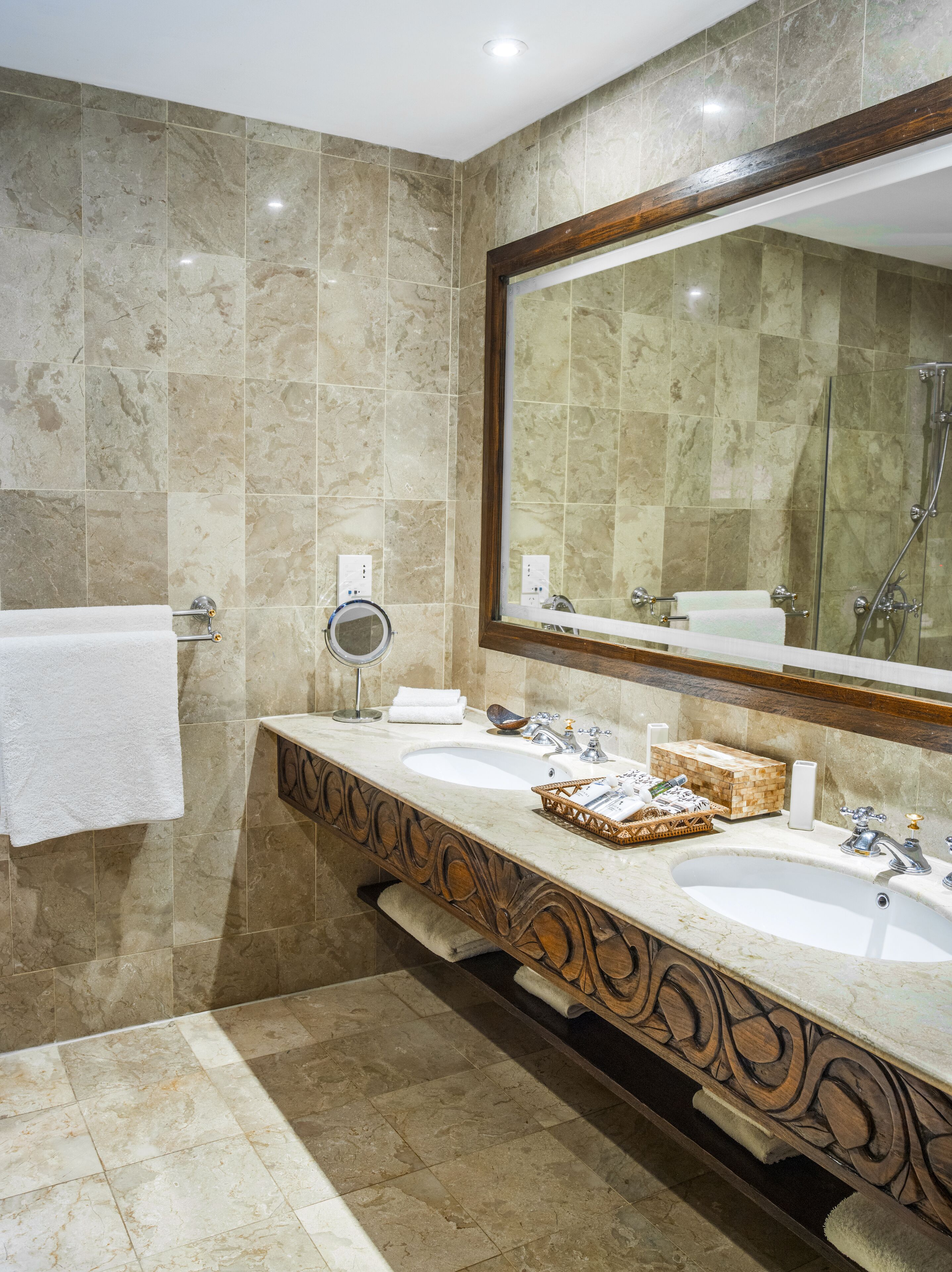 Une salle de bain avec deux lavabos, un grand miroir et une douche.